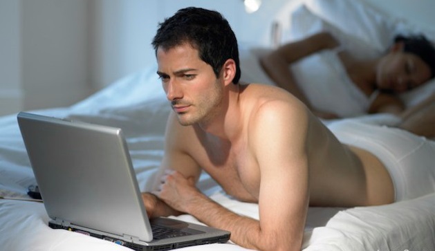 Man using laptop as wife sleeps